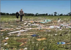  ?? The Associated Press ?? DEBRIS: Kyle Allen walks his parents' property in Canton, Texas on Sunday looking for personal items. Severe storms including tornadoes swept through several small towns in East Texas, killing several people, and leaving a trail of overturned vehicles,...