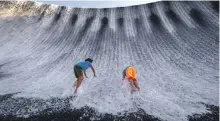  ?? Victor Besa / The National ?? Visitors play in the torrent that roars down the man-made waterfall at Expo 2020 Dubai