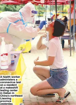  ??  ?? A health worker administer­s a coronaviru­s test on a resident at a makeshift testing center in Dalian in China’s northeast Liaoning province yesterday.