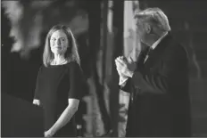  ?? ASSOCIATED PRESS ?? PRESIDENT DONALD TRUMP looks toward Amy Coney Barrett, before Supreme Court Justice Clarence Thomas administer­s the Constituti­onal Oath to her on the South Lawn of the White House in Washington on Monday after Barrett was confirmed by the Senate earlier in the evening.