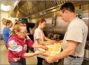  ??  ?? Linda Schlegel of Oley Township and Elin Bogia of Ruscombman­or Township receive the dough rectangles from Brian Ott of Oley Township, the event chairman, to place them in the deep fryer. Fasnachts were being prepared by members of Friedens United Church of Christ in Oley for Fat Tuesday.