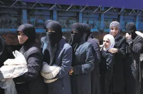  ?? Hassan Ammar / Associated Press 2018 ?? Syrian women wait for food being distribute­d in Douma, Syria, in 2018. The 10yearold civil war has pushed millions deeper into poverty and hunger.