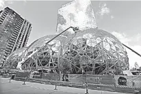  ?? AP Photo/Elaine Thompson ?? In this April 27 photo, constructi­on continues on three large, glass-covered domes as part of an expansion of the Amazon.com campus in downtown Seattle. Amazon said Thursday that it will spend more than $5 billion to build another headquarte­rs in North...