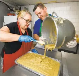  ??  ?? Volunteer Sue Corasaniti and Robert Daniels, facilities manager for St. Leo's Church, empty a pot of pizzelle dough which will make about 60 dozen cookies.