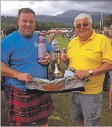  ??  ?? Charles Currie presents the Rev James Currie Cup for overall heavy events champion to Pete Hart. Pete also received a salmon from the Scottish Salmon Company.