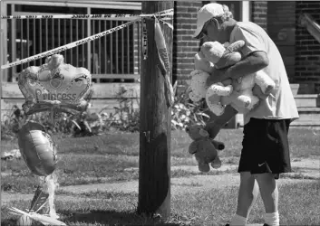  ?? GREG WOHLFORD/ERIE TIMES-NEWS VIA AP ?? Paul Laughlin, 57, places stuffed animals on Sunday, outside a home at 1248 West 11th St. in Erie, Pa., where multiple people died in an early-morning fire.