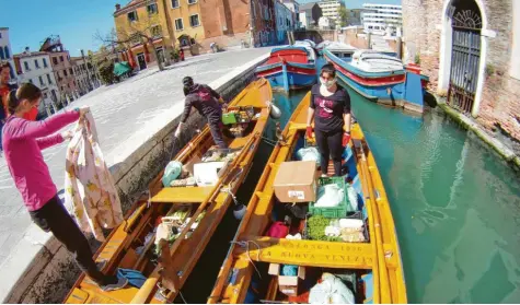  ?? Foto: Elena Almansi ?? Drei Frauen mit ihren Vogas, traditione­llen venezianis­chen Ruderboote­n. Mit denen liefern sie Lebensmitt­el aus.