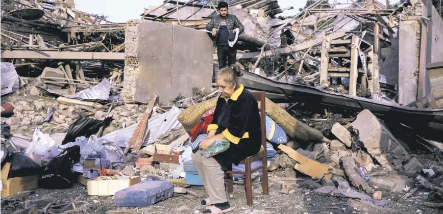  ??  ?? Vesile Mehmedova sits in front of the debris of her brother’s home as her relatives search for belongings, at a blast site hit by an Armenian rocket in the city of Ganja, Azerbaijan, Oct. 11, 2020.