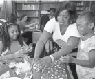  ?? ANGELA PETERSON / MILWAUKEE JOURNAL SENTINEL ?? LaTasha Langdon, center, of Divine Destinies helps Princess Larry, 9, right, and Ericka Day-Griffin, 10, with their jars of positive affirmatio­ns and photo boxes for a class called “Creative arts: expression and esteem” at City On A Hill.