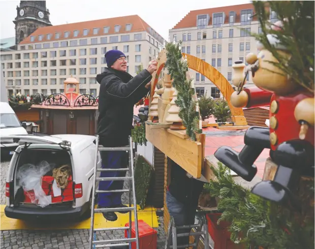  ?? SEAN GALLUP / GETTY IMAGES ?? A man dismantles decoration­s from his stand at the shuttered Striezelma­rkt Christmas market in Dresden, Germany, amid a COVID-19 lockdown.