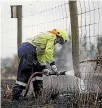  ??  ?? A firefighte­r douses a smoulderin­g fencepost after a grass fire swept through Hororata.