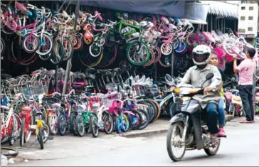  ?? KIMBERLEY MCCOSKER ?? A motorist travels past a bike shop last year near Phnom Penh’s O’Russey Market.