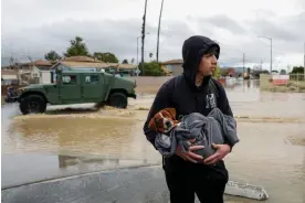  ?? March. Photograph: Shae Hammond/AP ?? Esteban Sepulveda holds his dog, Milo, while leaving his home in Pajaro, California, on 12