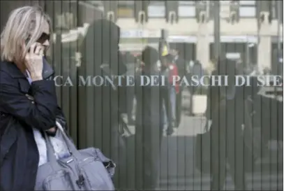  ?? LUCA BRUNO — THE ASSOCIATED PRESS FILE ?? In this Wednesday file photo, a woman walks past a Monte Dei Paschi di Siena bank branch in Milan, Italy. Zombies are gnawing at Europe’s underpower­ed economic recovery — zombie banks and zombie companies. Almost a decade after the financial crisis that ravaged the global economy, economists and top officials are warning that troubles in the banking system are keeping growth slow and unemployme­nt high.