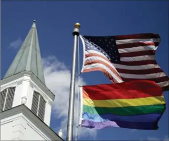  ?? CHARLIE RIEDEL — THE ASSOCIATED PRESS ?? In this file photo, a gay pride rainbow flag flies along with the U.S. flag in front of the Asbury United Methodist Church in Prairie Village, Kan. On Friday the United Methodist Church’s judicial council upheld the legality of major portions of a new plan that strengthen­s the denominati­on’s bans on same-sex marriage and ordination of LGBT pastors.