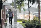  ?? AMY BETH BENNETT/SOUTH FLORIDA SUN SENTINEL ?? A woman walks in the rain down Andrews Avenue in Oakland Park on Friday morning. The first storm of the 2020 hurricane season may form in the next 24 hours.