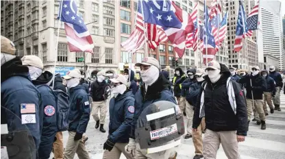  ?? PAT NABONG/SUN-TIMES FILE ?? Members of Patriot Front, a group the Southern Poverty Law Center has classified as a white nationalis­t hate group, march down Michigan Avenue as anti-abortion activists march across the street during a March for Life rally in January.