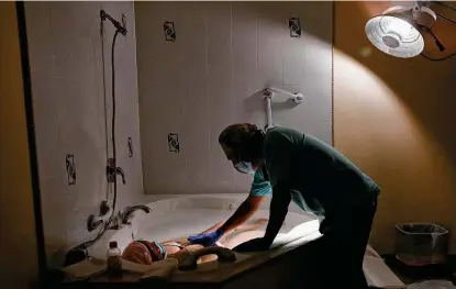  ??  ?? Licensed midwife Ruben Casillas checks on Arleth Garcia as she labors in a tub. Casillas is the only licensed midwife in Laredo.