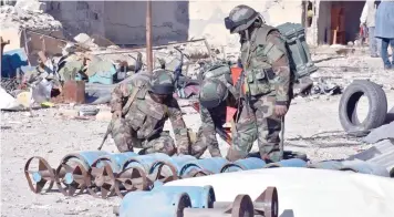  ?? — AFP ?? Syrian pro-government forces inspect home-made rockets used by rebels in Aleppo’s Masaken Hanano neighbourh­ood a few days after the area was retaken by the troops.