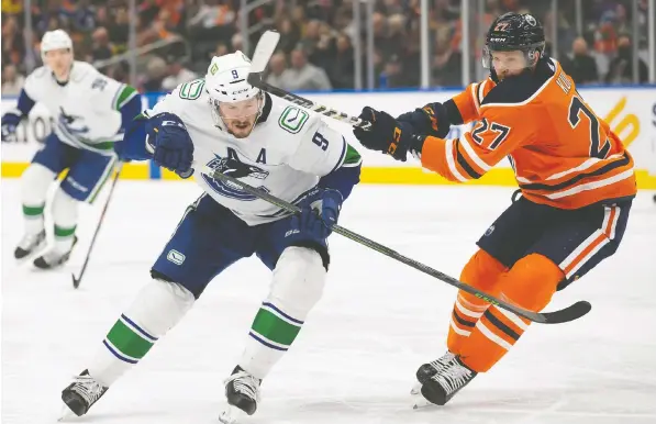  ?? GETTY IMAGES ?? The Canucks' J.T. Miller, left, fends of the Oilers' Brett Kulak during the two teams' final game of the season Friday night in Edmonton.