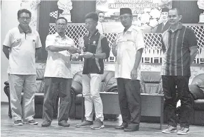  ??  ?? PEMAIN terbaik Mohd Izzat Emir Zaki Yudin dari SMKA Keningau menerima piala daripada Mohd. Azhari. Turut kelihatan dalam gambar ialah Hamiun Suani (kiri), Kapten Mohd Rizal(kanan sekali) dan Haidon(dua dari kanan).