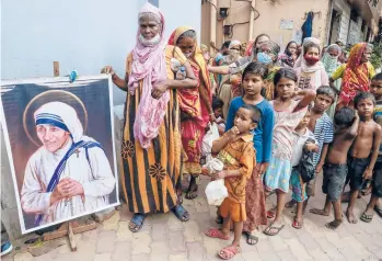  ?? BIKAS DAS/AP ?? Homeless people gather Thursday beside a portrait of St. Teresa, the founder of the Missionari­es of Charity, to collect food outside the order’s headquarte­rs in Kolkata, India. Thursday marked the birth anniversar­y of Mother Teresa, a Catholic nun who spent 45 years serving the poor, the sick, the orphaned and the dying. She was born in 1910 and died in 1997.