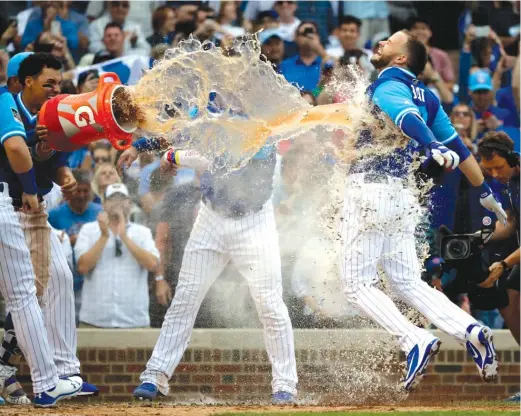  ?? NAM Y. HUH/AP ?? David Bote (right) takes a tank of Gatorade to the chest after his solo homer off the Reds’ Raisel Iglesias in the 10th inning Friday won the game for the Cubs.