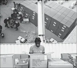  ?? AP ?? In an image from video in October, people work inside the UNICEF warehouse in Copenhagen, Denmark, where the groundwork is being laid for the COVAX initiative.