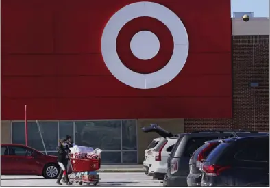  ?? (AP) ?? Shoppers push a full cart of their purchases to a car outside the Target store in the South Bay neighborho­od of Boston, in this file photo. Target on Wednesday posted quarterly net income of $712 million, or $1.54 per share, down from $1.49 billion, or $3.04 per share, a year ago.