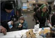  ?? RODRIGO ABD — THE ASSOCIATED PRESS ?? Vlad, 6, drinks milk next to his father Ivan, 40, at a donated food distributi­on stand in Bucha, in the outskirts of Kyiv, Ukraine, Saturday. Vlad’s mother died during their confinemen­t in a basement for more than a month during the occupation of the Russian army.