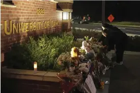  ?? Photograph: Ted S Warren/AP ?? Two people place flowers at a growing memorial in front of a campus entrance sign for the University of Idaho on 16 November 2022 in Moscow, Idaho.