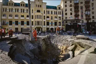  ?? Andrii Marienko / Associated Press ?? Workers examine a crater from a Russian rocket attack that struck Kharkiv in northeaste­rn Ukraine. About 180 miles to the south, fighting near a nuclear plant has stirred safety fears.