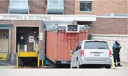  ?? ROB GURDEBEKE THE CANADIAN PRESS ?? A grey minivan belonging to a local funeral home parks in front of a storage container that’s been converted into a temporary morgue at the rear of Windsor Regional Hospital Met Campus in Windsor, Ont., on Wednesday.