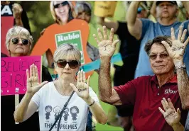  ?? JAMES WOOLDRIDGE PHOTOS / THE PALM BEACH POST ?? Protesters take a moment of silence Thursday after a group portrait showing opposition to Brett Kavanaugh’s Supreme Court nomination outside Sen. Marco Rubio’s office on PGA Boulevard in Palm Beach Gardens.