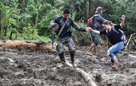  ?? Photo by Redjie Melvic Cawis ?? PCOO Assistant Secretary Marie Rafael Banaag traverses a landslide on her way to Natonin to personally reach out to the landslide affected area in Sitio Ha’rang, Barangay Banawel where more than 20 people were buried and washed out during typhoon Rosita. Banaag was a former mayor of the town.