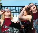  ?? AP FILE ?? Southern Illinois University cheerleade­rs try out eclipse glasses given out for the 2017 total solar eclipse, which cast Carbondale and parts of 14 states besides Illinois in darkness. The community will again be in the path of totality for the April 8 solar eclipse.