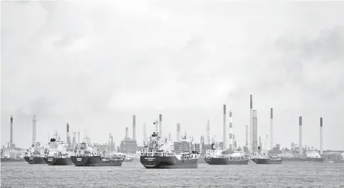  ??  ?? Ships are seen anchored in front of a refinery on Singapore’s Bukom Island. — Reuters photo