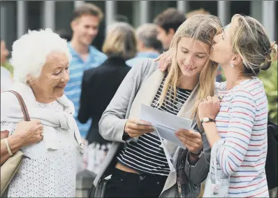  ??  ?? Phoebe Crane gets a kiss from her mother as she opens her A-level results, at Norwich School, Norwich.