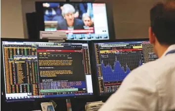  ?? Reuters ?? An investment manager watches Britain’s Prime Minister Theresa May speaking in the House of Commons in London yesterday. London’s financial services sector is not convinced about the deal given the political certainty.