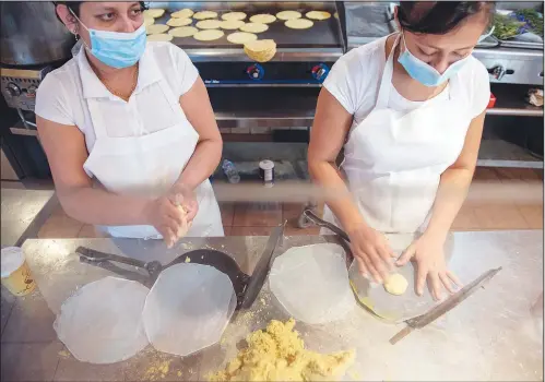  ?? (AP/Camden Courier-Post/Joe Lamberti) ?? Maria Ramos (left) and Marilu Ovelo prepare tortillas Dec. 3 at South Philly Barbacoa in Philadelph­ia.