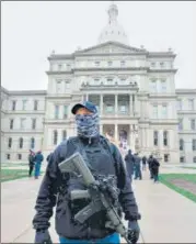  ?? AFP ?? A protester, part of ‘Michigande­rs Against Excessive Quarantine’ n march, stands with a gun near Michigan State Capitol.