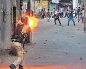  ?? PTI ?? A policeman fires a tear gas shell towards the protesters hurling stones at forces in Srinagar on Saturday.