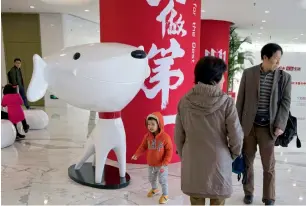  ?? — AP ?? a child stands near the mascot for jD.com and the words for ‘Be Number One’ at its headquarte­rs in Beijing, China. Google seeks to expand in fast-growing asian e-commerce markets.