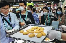  ?? ZHANG HENGWEI / CHINA NEWS SERVICE ?? Visitors line up in front of an exhibitor from the United States offering artificial chicken during the third China Internatio­nal Import Expo in Shanghai last month.