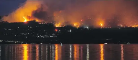  ?? DARRYL DYCK, THE CANADIAN PRESS ?? The McDougall Creek wildfire burns on the mountainsi­de above lakefront homes in West Kelowna on Aug. 18, 2023.