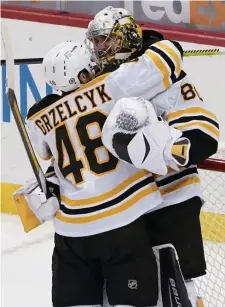  ?? Ap pHotos ?? SPECIAL MOMENT: Matt Grzelcyk celebrates with Bruins goaltender Daniel Vladar after the rookie notched a victory in his first career start Tuesday night against the Penguins. At right, Brad Marchand watches after passing the puck past Pittsburgh’s Cody Ceci.
