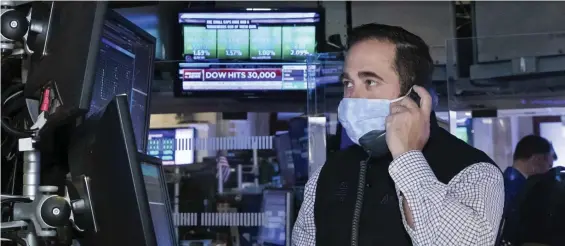  ?? Ap ?? KEEP IT COMING: A trader at the New York Stock Exchange works at his terminal Tuesday, when the Dow Jones Industrial Average traded above 30,000 points for the first time.