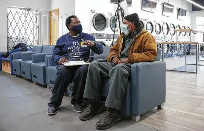  ?? Teresa Crawford / Associated Press ?? Herman Simmons, left, makes a vaccinatio­n appointmen­t for Theopulis Polk at a Chicago laundromat this month.