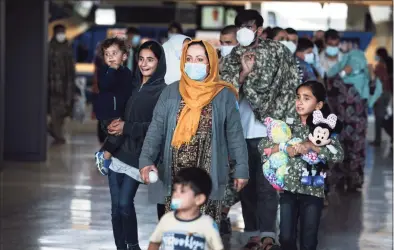  ?? Anna Moneymaker / Getty Images ?? A family evacuated from Afghanista­n are led through the arrival terminal at Dulles Internatio­nal Airport in Virginia on Wednesday to board a bus that will take them to a refugee processing center.