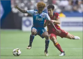  ?? The Canadian Press ?? Vancouver Whitecaps’ Yordy Reyna, left, and Real Salt Lake’s Tony Beltran vie for the ball duringfirs­t-halfMLSact­ioninVanco­uveronSatu­rdaynight.TheWhiteca­pswon3-2.